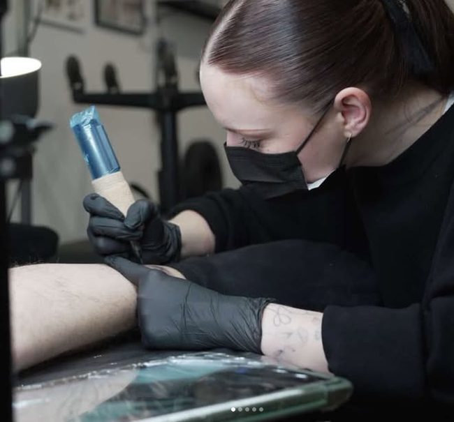Amobrius en train de tatouer, gants noirs, machine à la main