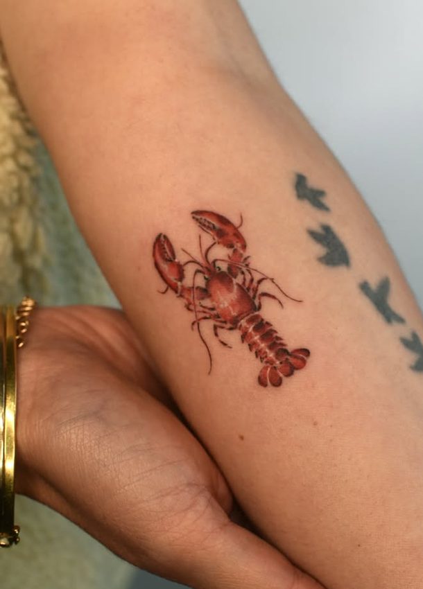 Tatouage d'un petit homard rouge sur l'avant-bras